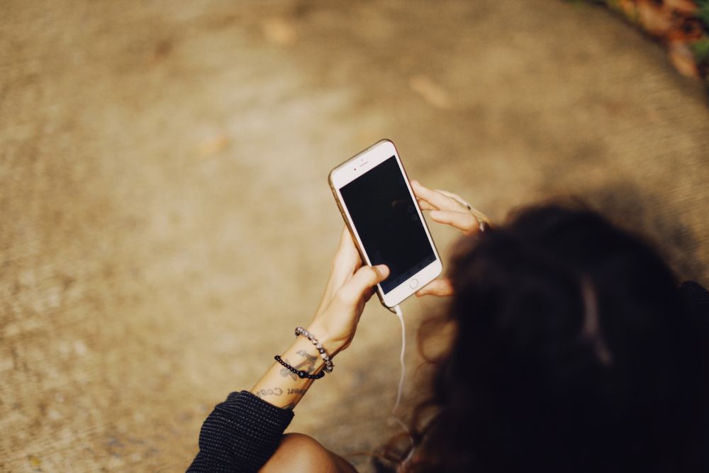 Een vrouw gebruikt buiten haar telefoon met oordopjes