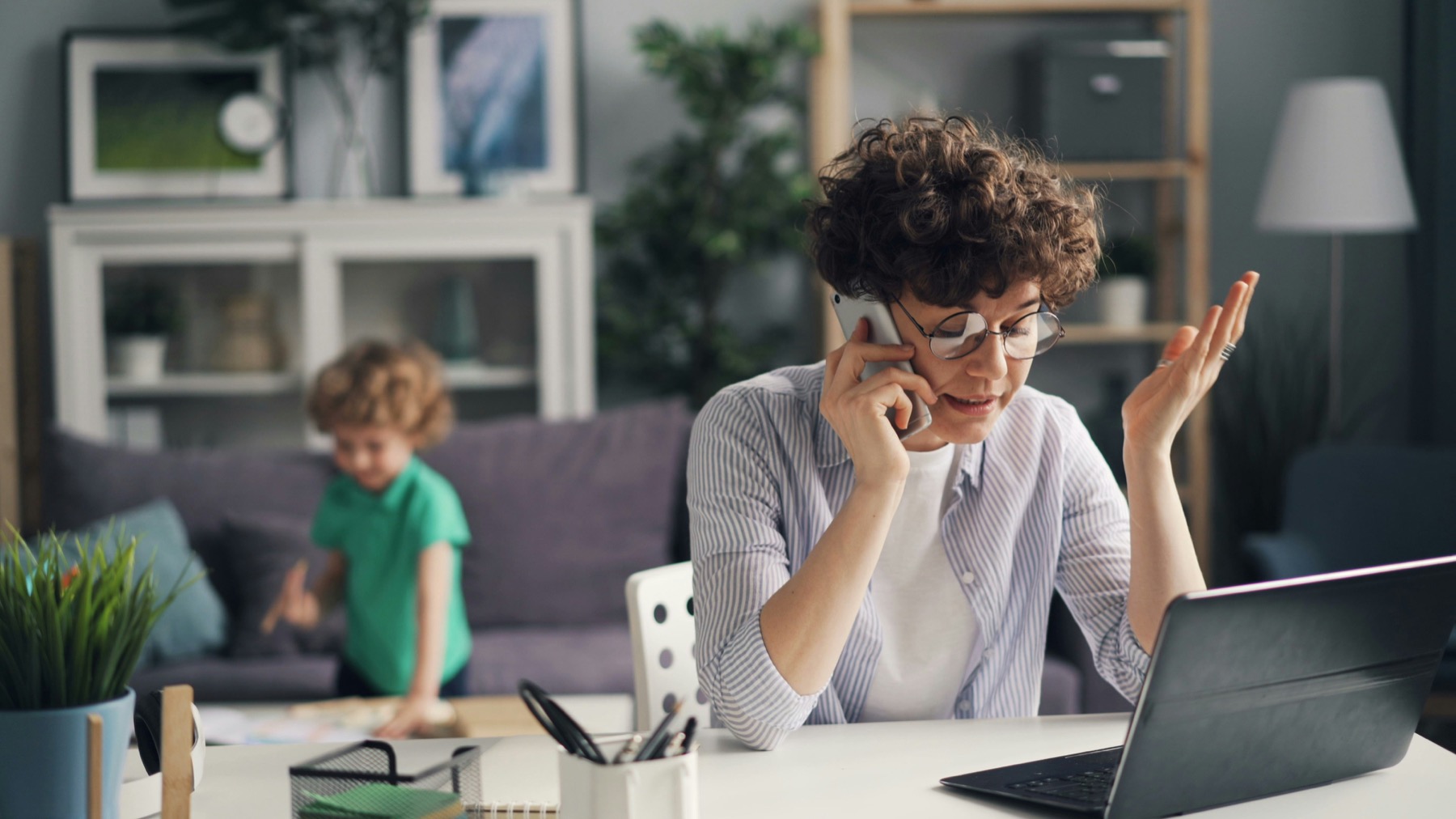 Persoon die tijdens een telefoongesprek kritisch naar een laptop kijkt