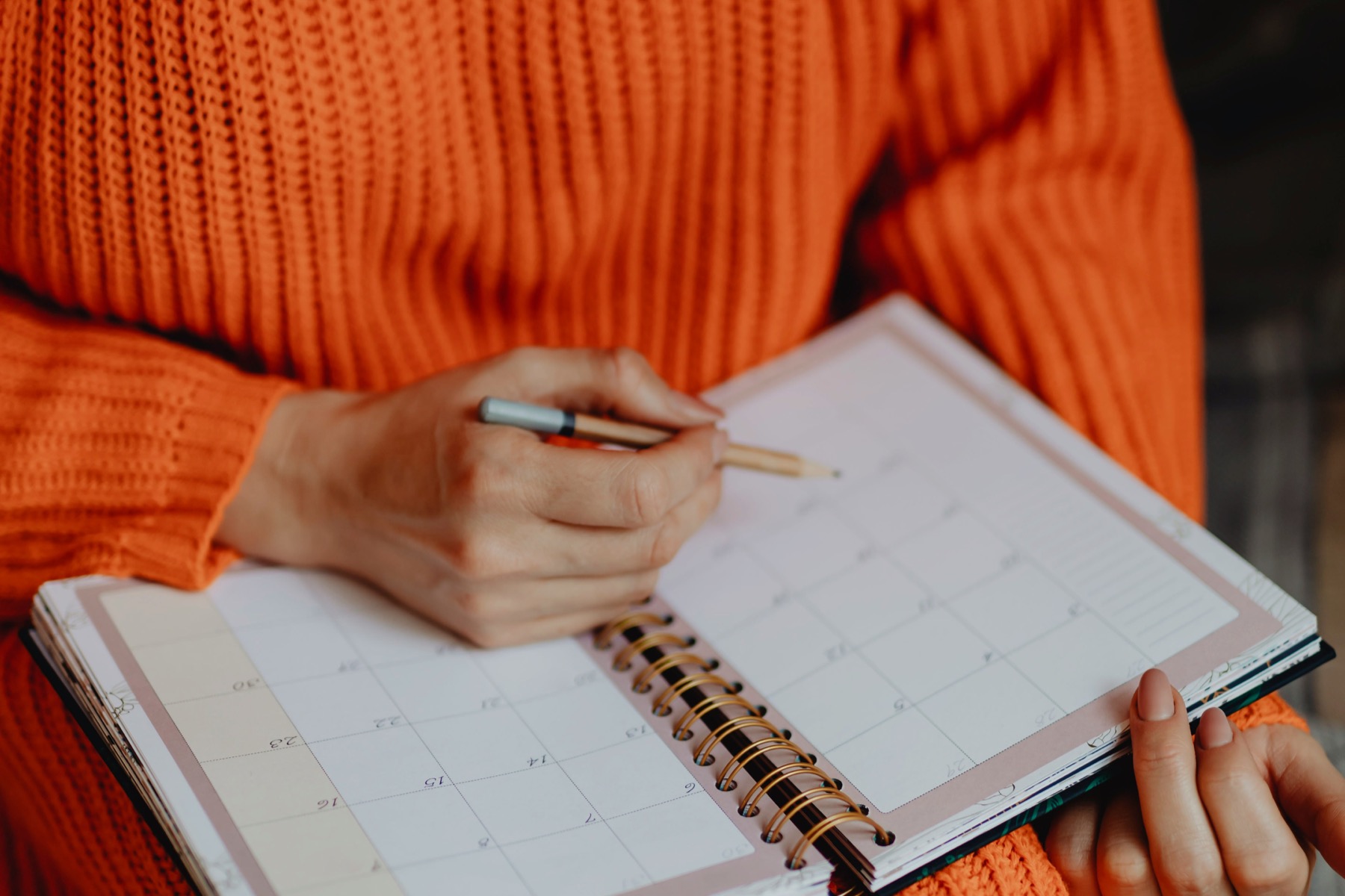 Persoon die een datum noteert in een papieren kalender