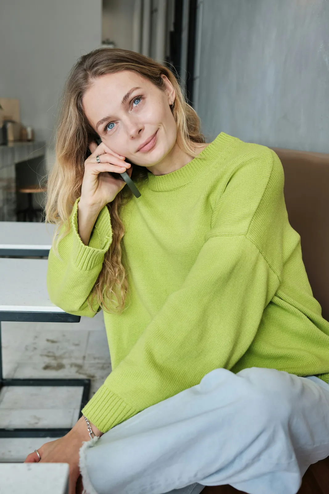 Vrouw in een lime trui belt en lacht