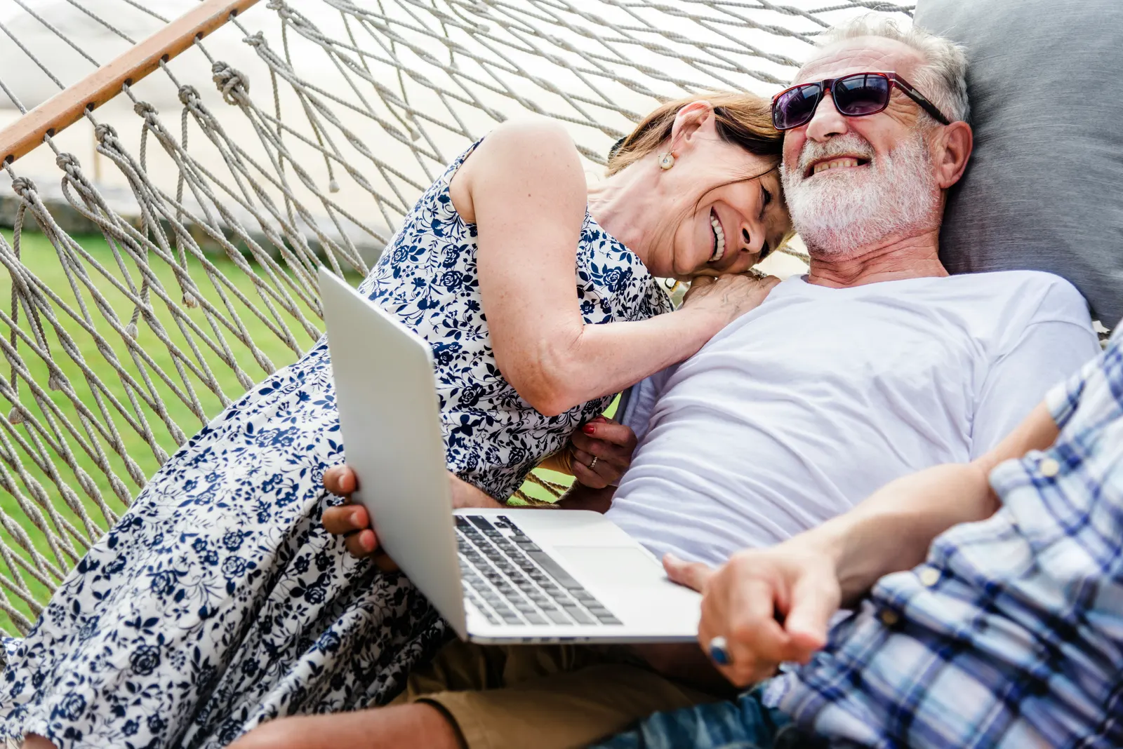 Lachend stel in een hangmat met een laptop